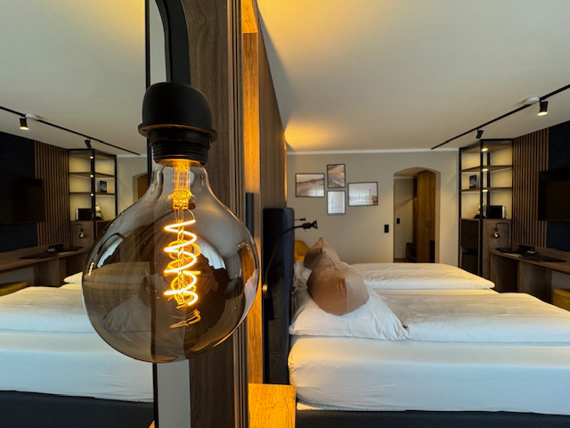 Doppelzimmer im Hotel Ennen, Nahaufnahme einer großen Glühbirne, im Hintergrund ist das Zimmer erkennbar.