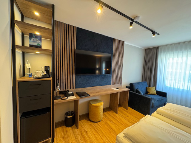 XL Doppelzimmer im Hotel Ennen, Blick auf Regal und Fernsehwand, rechts davon befindet sich ein Sessel
